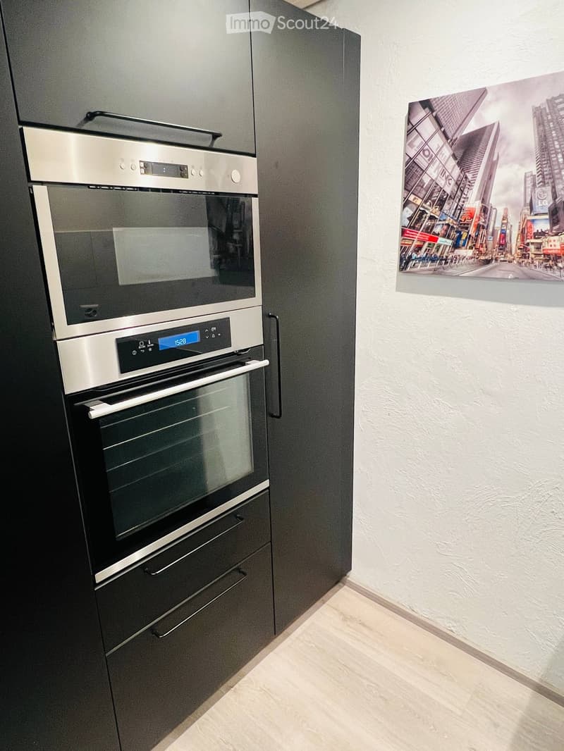 Modern kitchen with a built-in oven and a large cityscape poster on the wall.