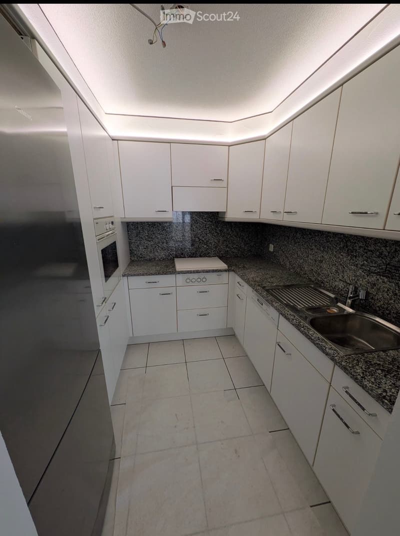 Modern kitchen with white cabinets, granite countertops, and a stainless steel sink. Features include an oven and ample storage space.