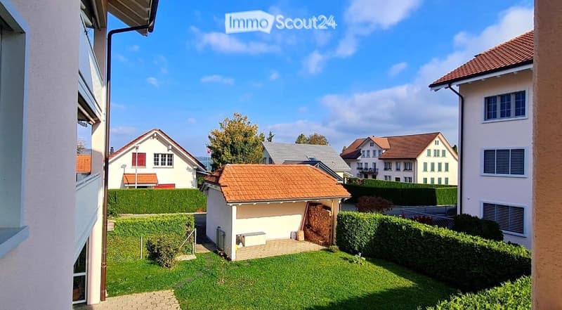 A well-maintained garden area with a small shed, neatly trimmed hedges, and a paved pathway leading to the house.