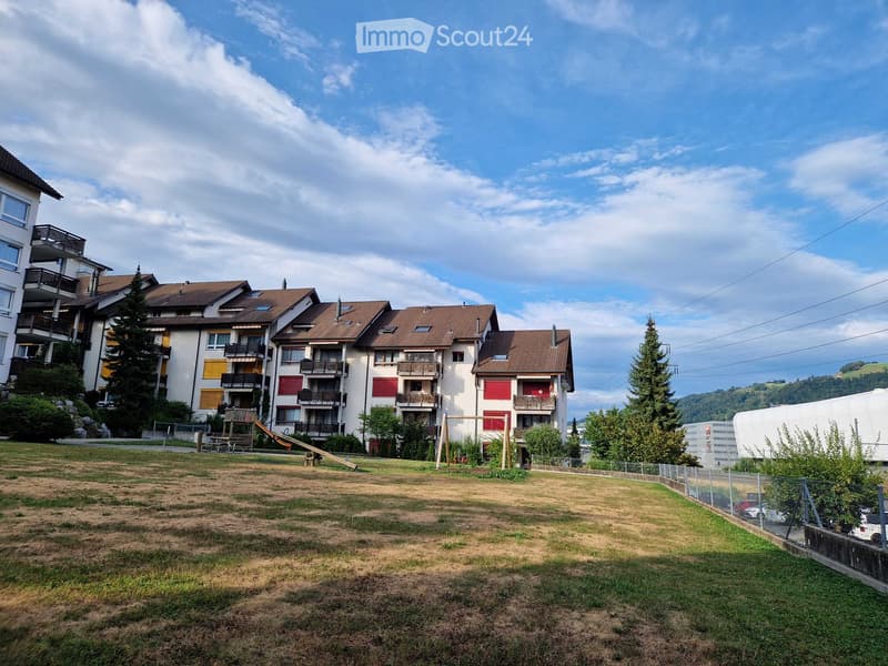 Residential building with multiple apartments, balconies, and a playground area in front.