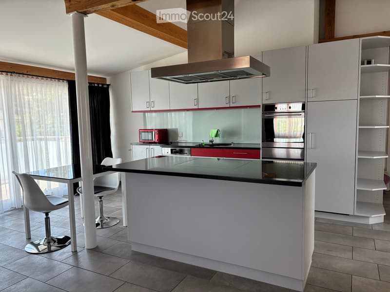 Modern kitchen with white cabinets, stainless steel appliances, island, and seating area.