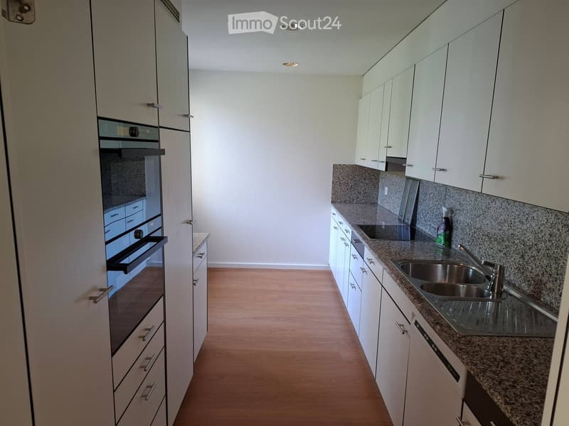 Modern kitchen with white cabinets, granite countertops, stainless steel sink, and built-in oven.