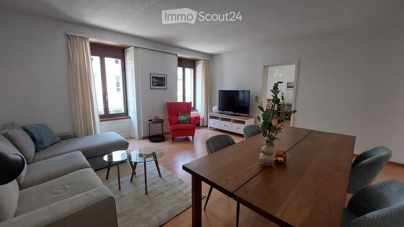 Dining room: table with chairs, living room visible in the background, TV, lamp