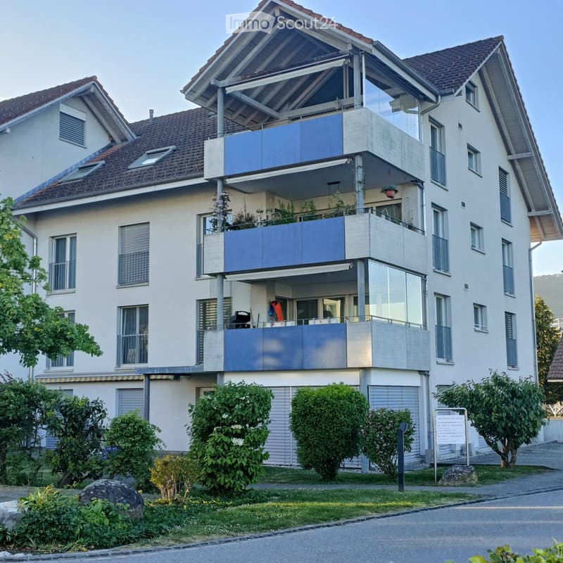 Modern two-story house with multiple balconies, large windows, and a well-maintained garden.