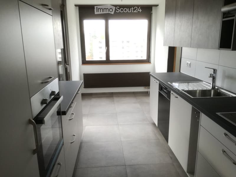 Modern kitchen with white cabinets, black countertops, stainless steel sink, and built-in appliances.