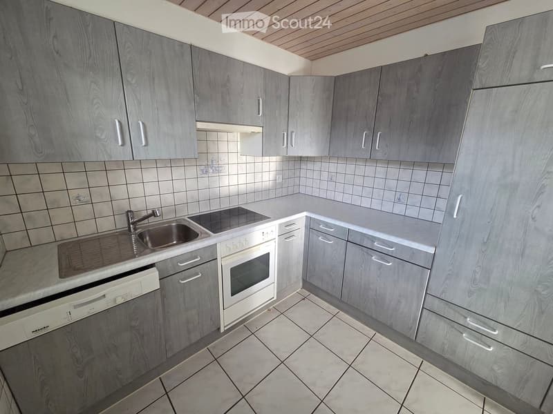 Modern kitchen with grey wooden cabinets, white appliances, and tiled walls.