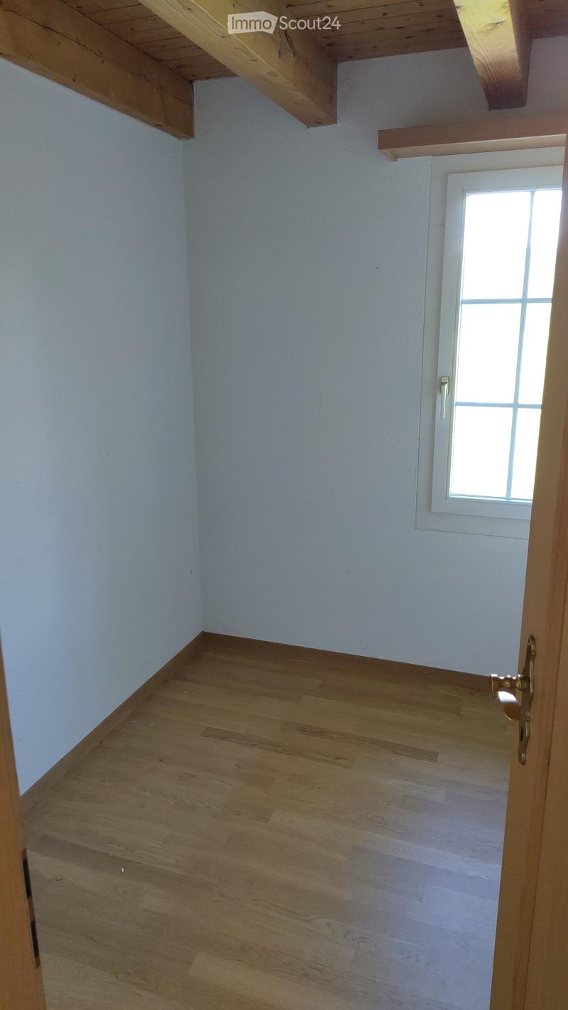 Unfurnished Room. Empty room with light blue walls and wooden flooring, featuring a small window and exposed wooden beams on the ceiling.