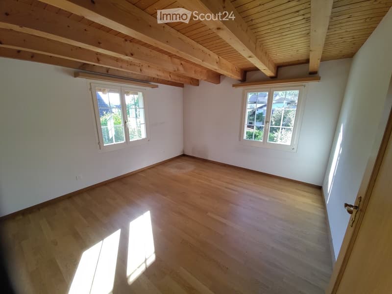 Unfurnished Room. Empty room with wooden flooring, white walls, and exposed wooden ceiling beams. Two windows provide natural light, and the space is unfurnished.