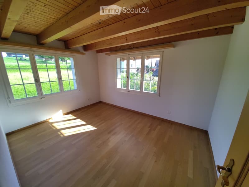 Unfurnished Room. Empty room with wooden flooring, white walls, large windows, and exposed wooden ceiling beams.