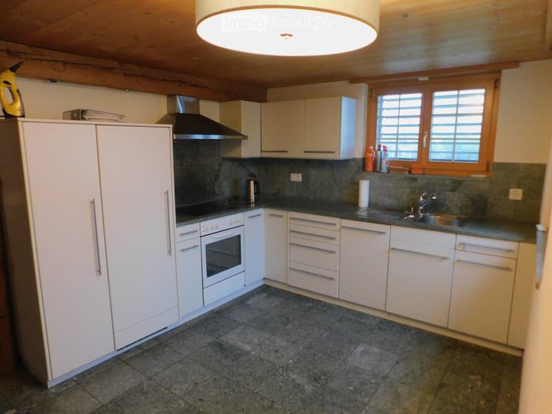 Modern kitchen with white cabinets, stainless steel appliances, granite countertops, and a dark tiled floor.