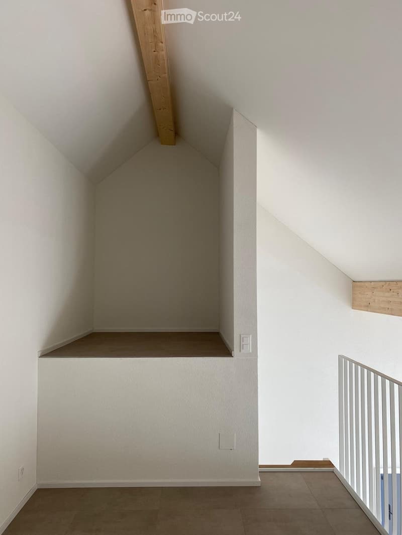 Empty room with white walls, wooden floor, and a small raised platform area. No furniture or equipment visible.