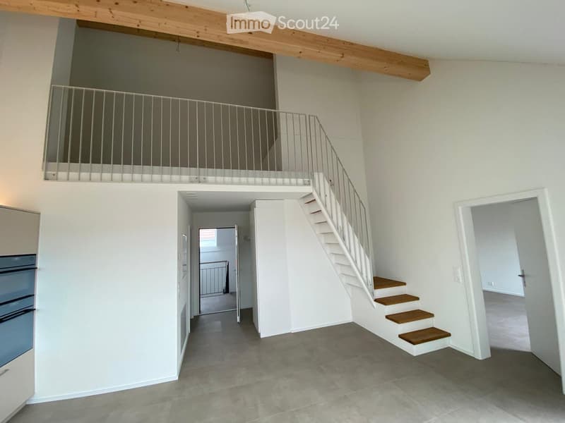 Open hallway with a staircase leading to an upper level, featuring a metal railing and wooden steps, with a balcony overlooking the space.