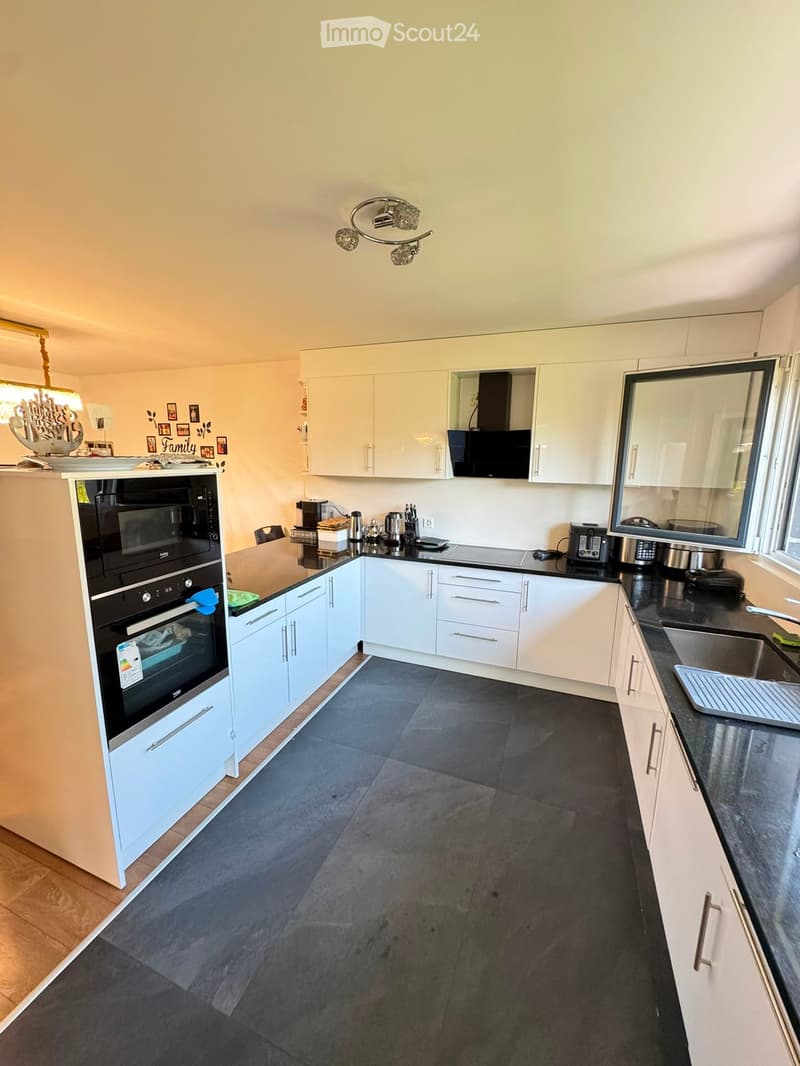 Modern kitchen with white cabinets, black countertops, and stainless steel appliances including an oven, microwave, and sink.