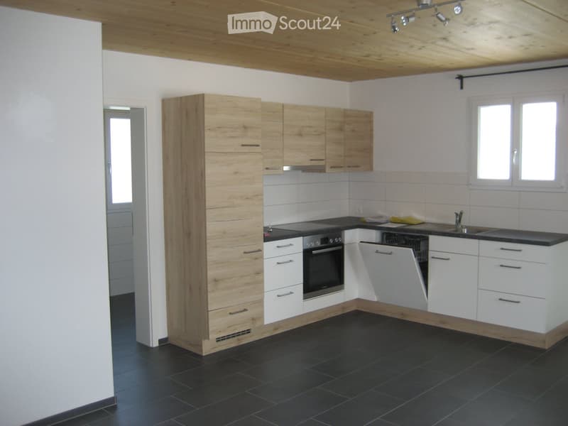 Modern kitchen with wooden and white cabinets, black countertops, and a built-in oven. Features a sink with a faucet and a window above the counter.