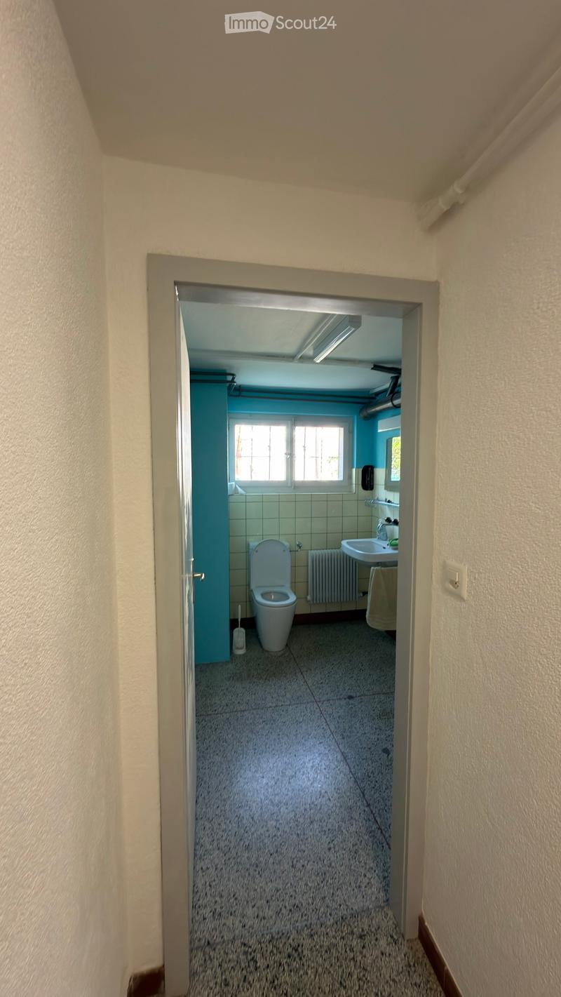 Bathroom with a toilet, sink, and window. The room has tiled walls and a radiator.