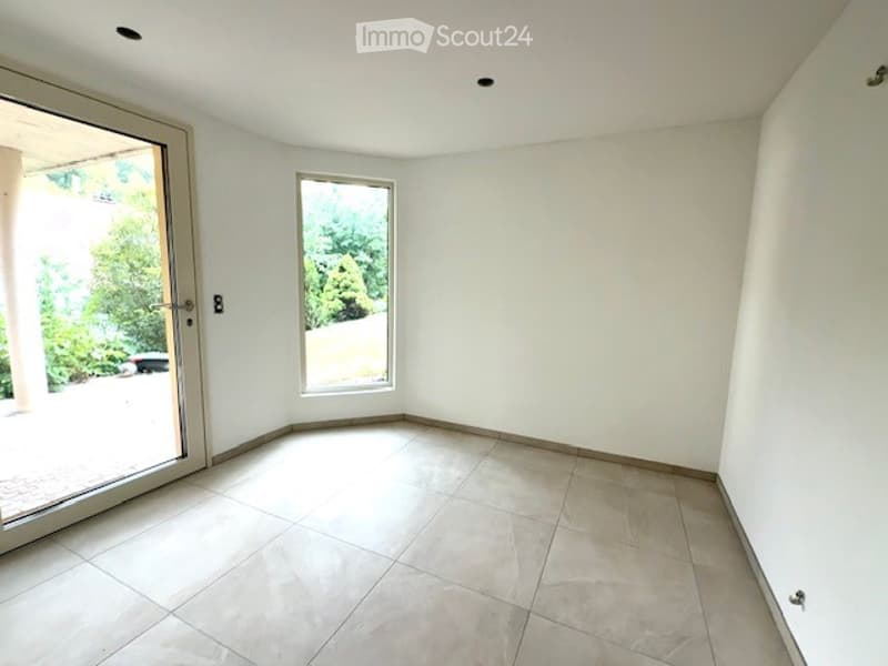 Empty room with white walls, tiled floor, large window, and sliding glass door leading to an outdoor area.
