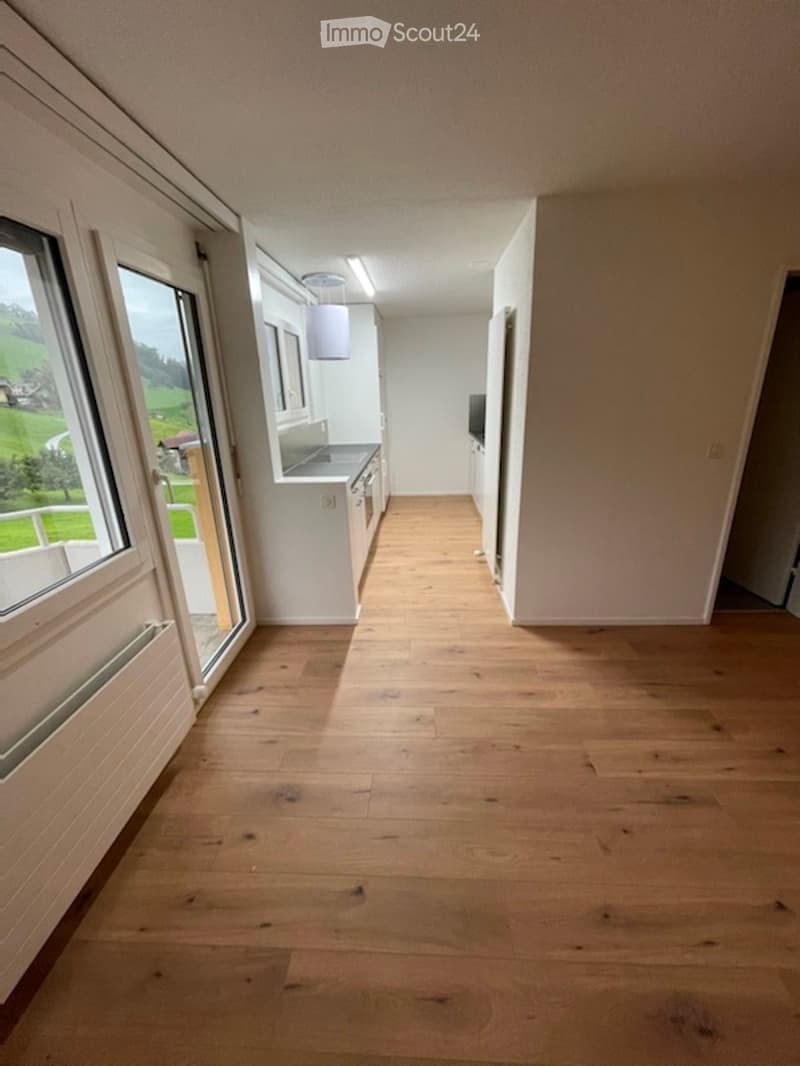 A small, compact room with wooden walls and a skylight window, featuring a built-in cabinet and a small sink area.