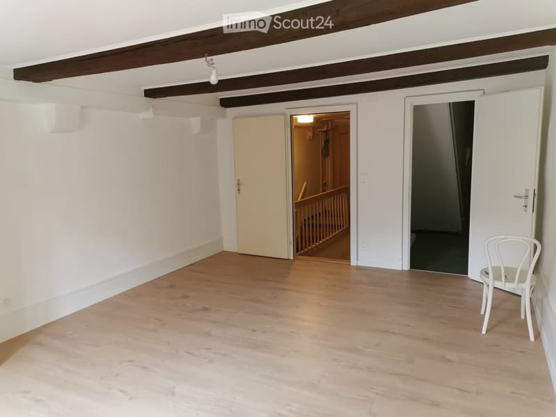 empty room, wooden floor, white walls, wooden beams, two doors, one leading to stairs
