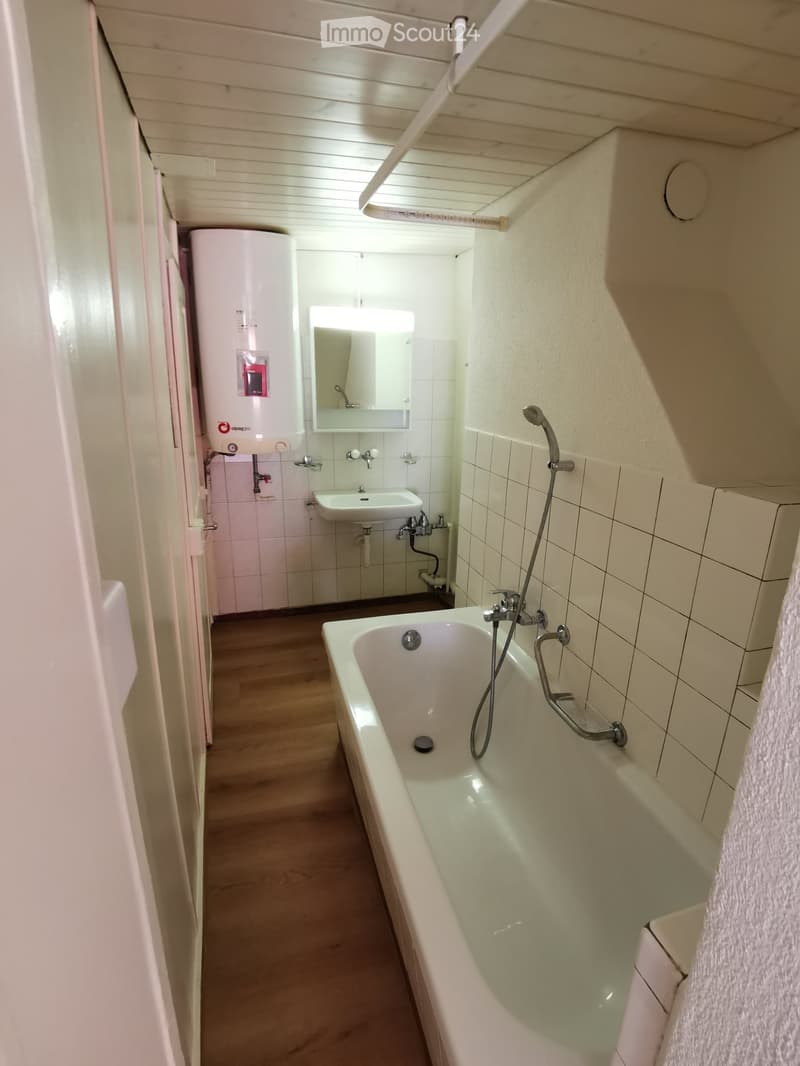 Bathroom with bathtub, sink, water heater, white tiles, wooden floor