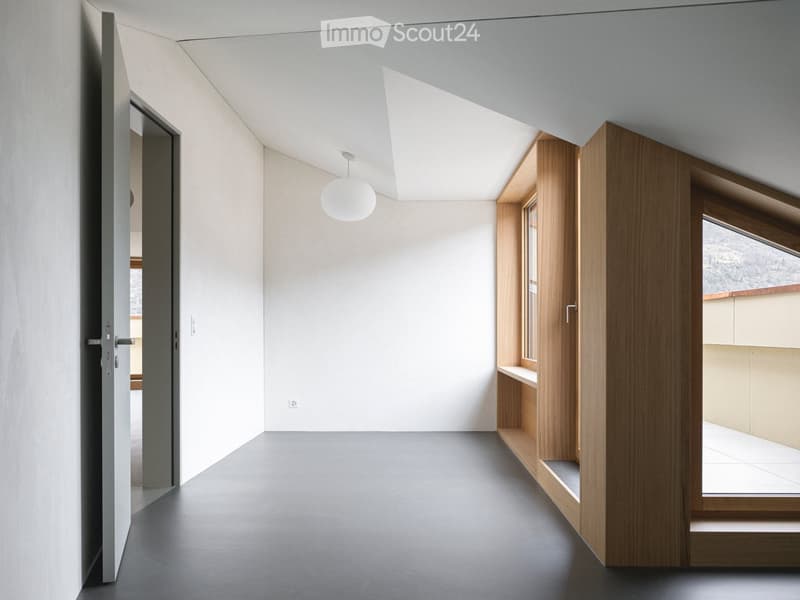 Modern, minimalist hallway with grey walls, dark grey floor, and a single pendant light fixture. Features a wooden shelving unit and a large window with a view.