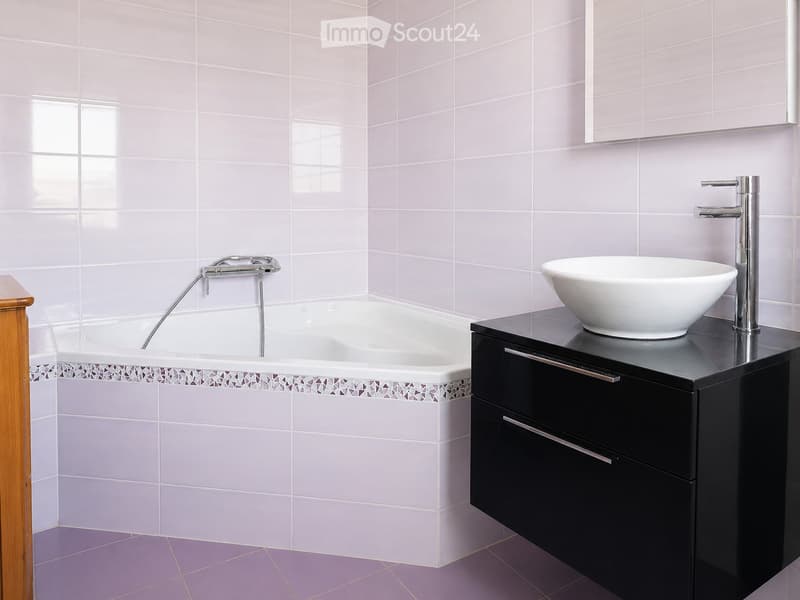 Modern bathroom with a white bathtub, a black vanity with a white sink, and a chrome faucet.