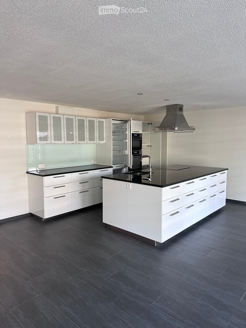 Modern kitchen with white cabinets, black countertops, stainless steel appliances, and dark tiled flooring.