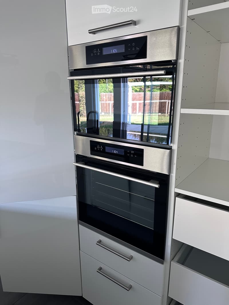 Modern kitchen with built-in stainless steel ovens and white cabinets.