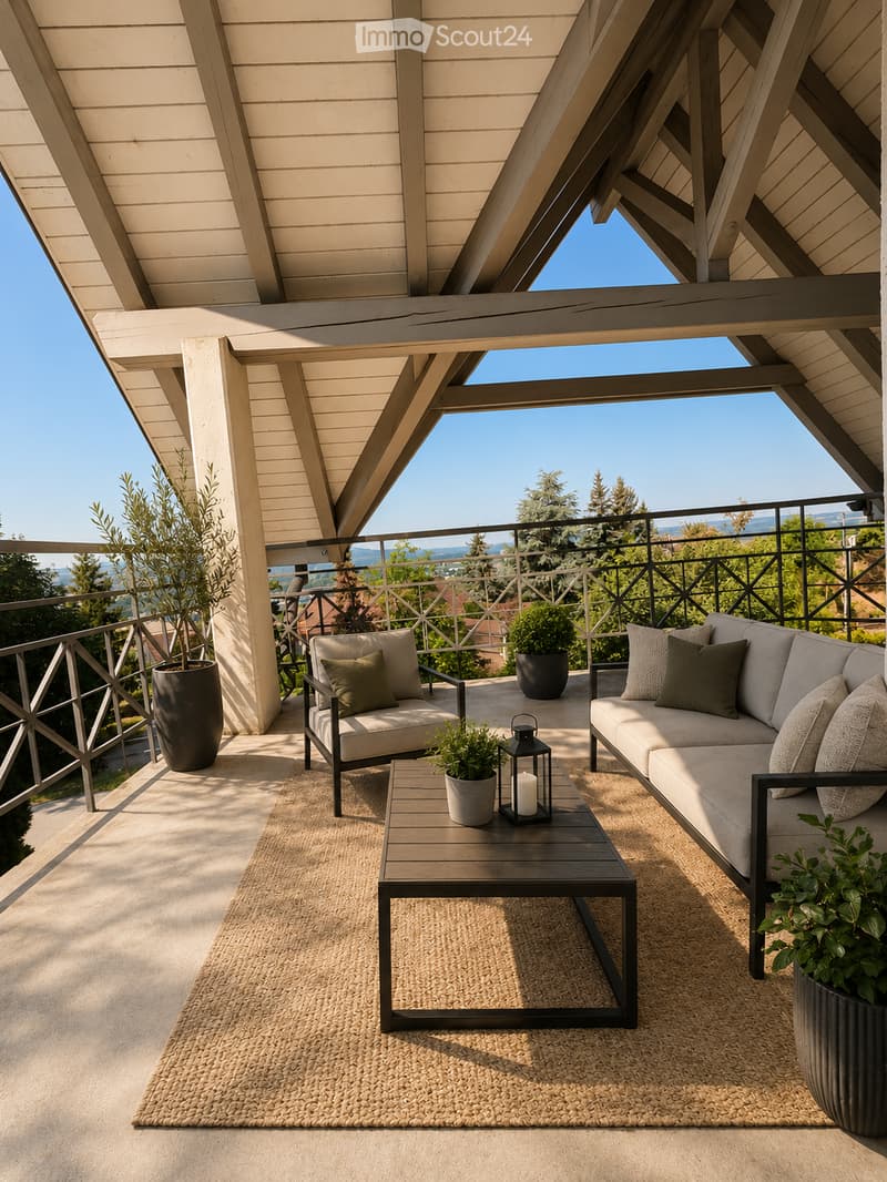 A modern balcony with a sectional sofa, coffee table, armchair, rug, lantern, and potted plants, overlooking a scenic view.