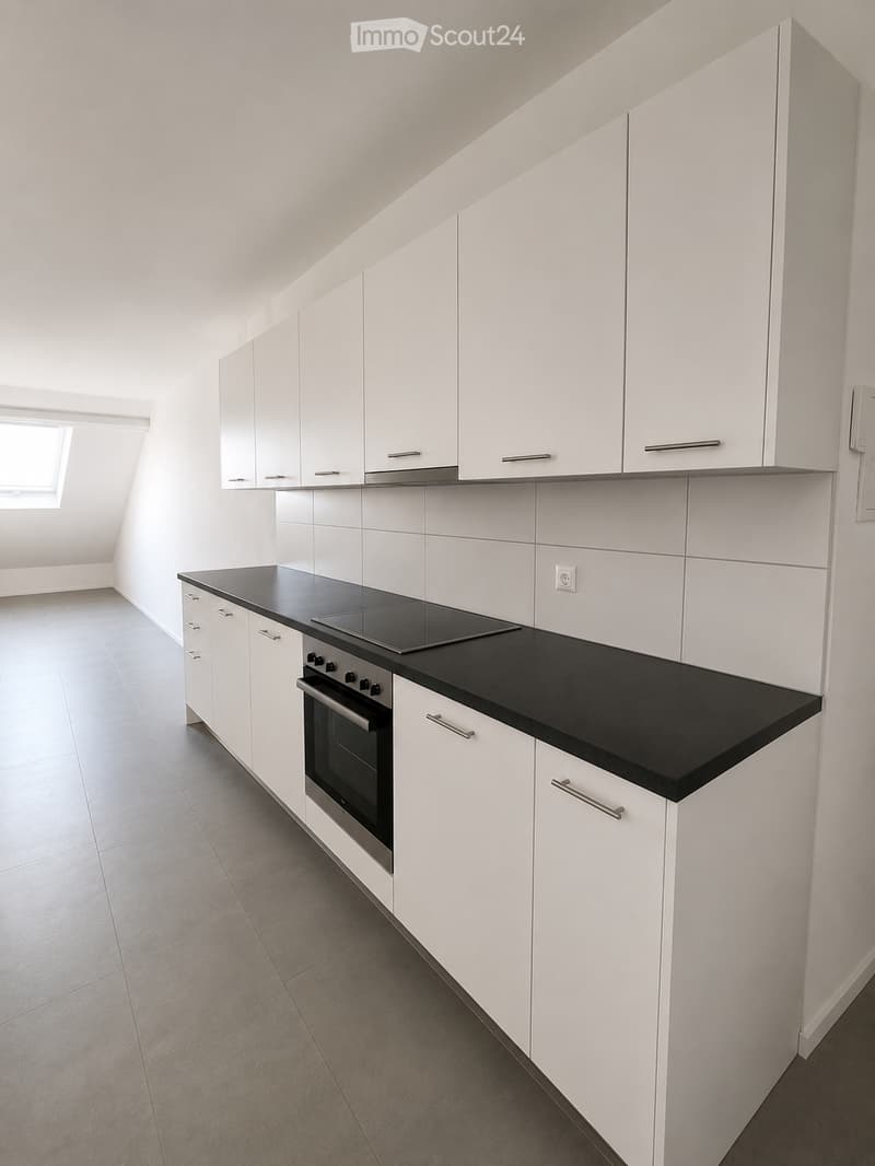 Modern kitchen with white cabinets, black countertop, induction cooktop, and built-in oven.