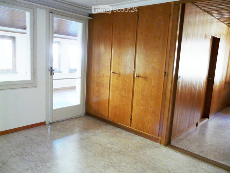 Empty room with wooden panel walls, tiled floor, and a large sliding glass door leading to an outdoor area.