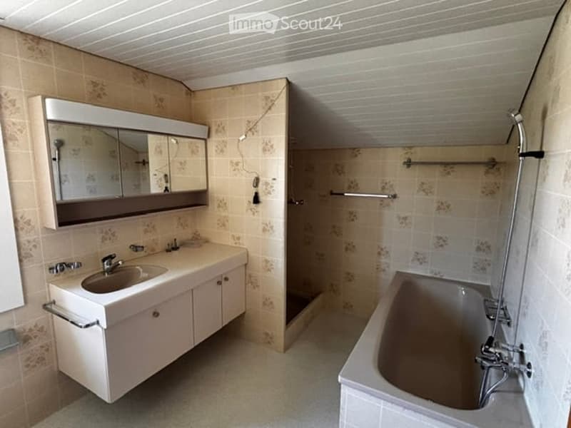 Bathroom with a double sink vanity, mirror, bathtub, and tiled walls and floor.