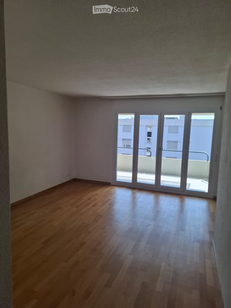 Empty room with wooden flooring and large sliding glass doors leading to a balcony.