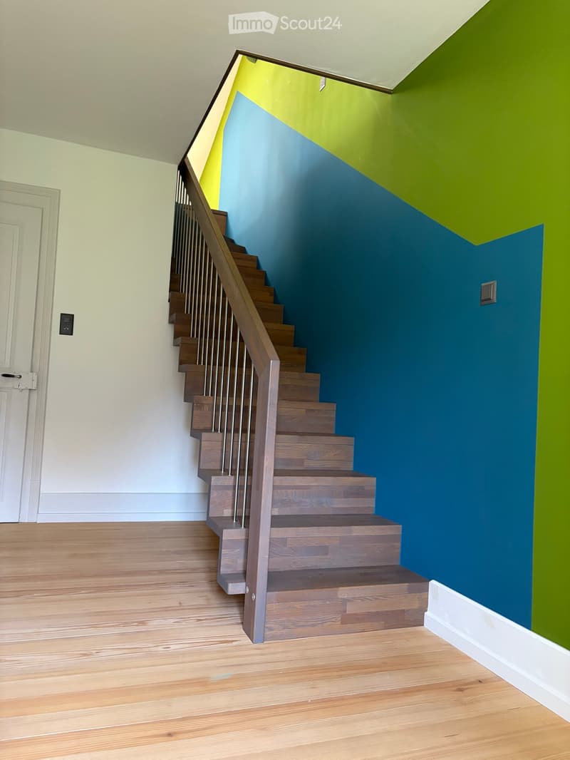 Wooden staircase with metal railing, light-colored walls, and wooden flooring.