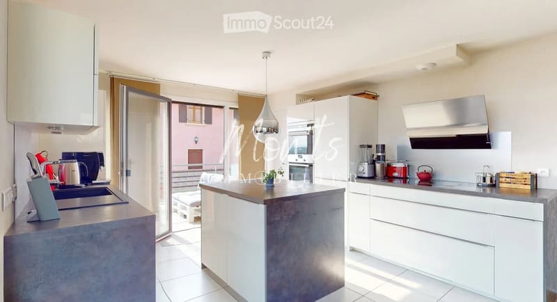 Modern kitchen with white cabinets, grey island, stainless steel appliances, and various kitchen items on the counters.