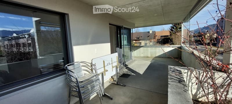 Balcony with modern furniture, large windows, and scenic mountain view.