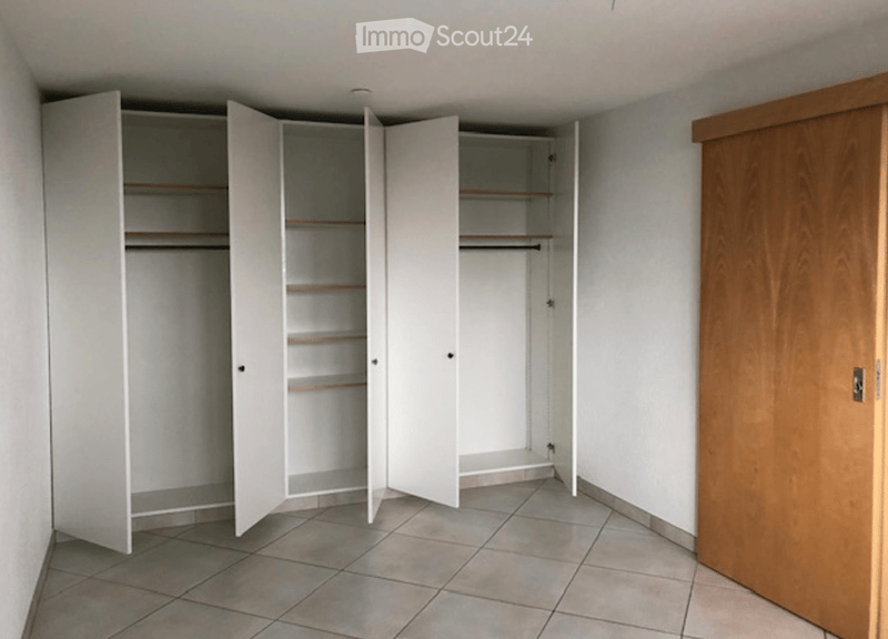 Empty room with tiled floor, white walls, and built-in white closet with multiple shelves and hanging space.