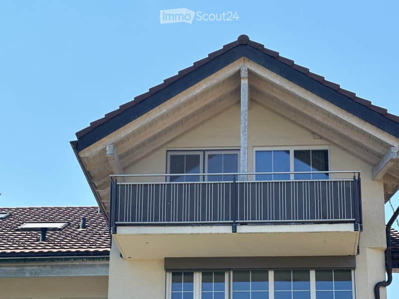 Two-story residential building with a tiled roof, balcony, and large windows.