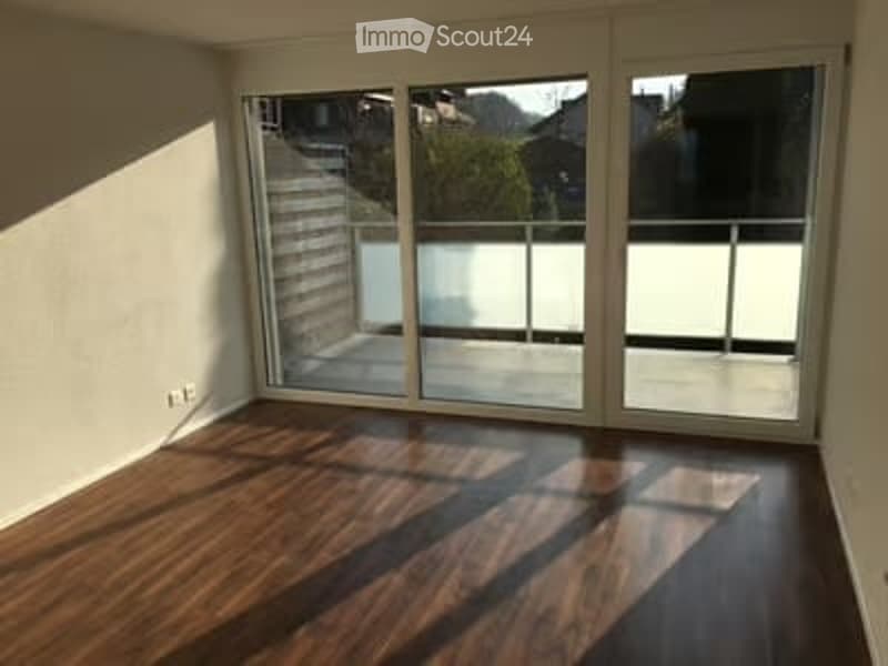 Empty room with wooden flooring and large sliding glass doors leading to a balcony.