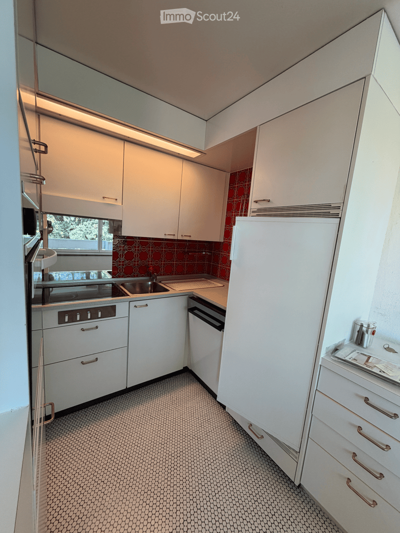Modern kitchen with white cabinets, stainless steel appliances, and a patterned tile floor.
