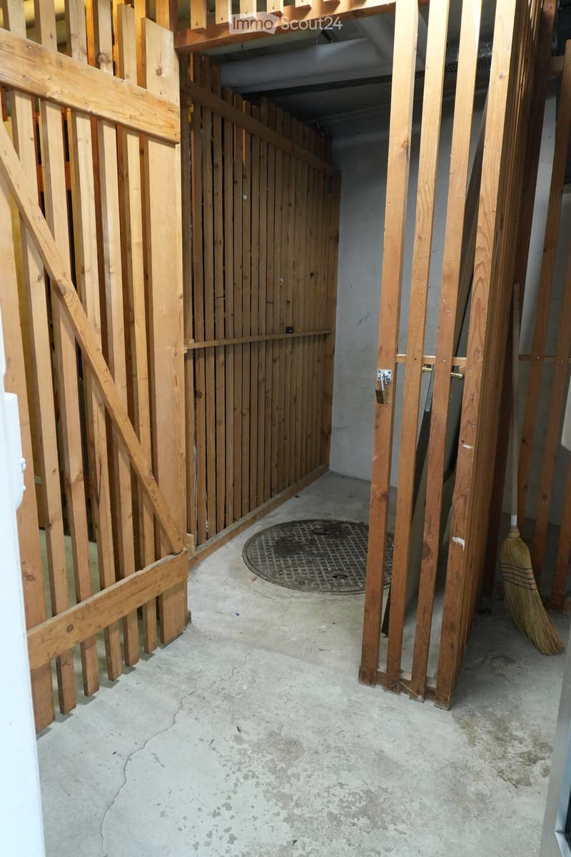 Empty hallway with exposed wooden framing, concrete floor, and a metal grate in the center.