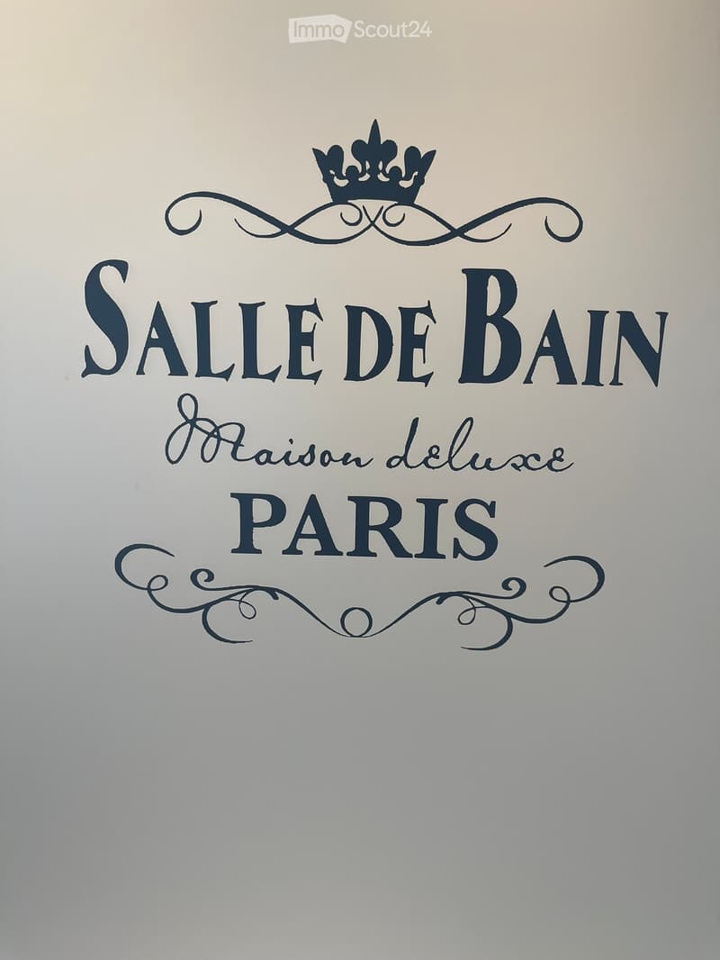 Elegant bathroom wall with a decorative sign reading "SALLE DE BAIN Raison Deluxe PARIS" featuring ornate typography and a crown emblem.