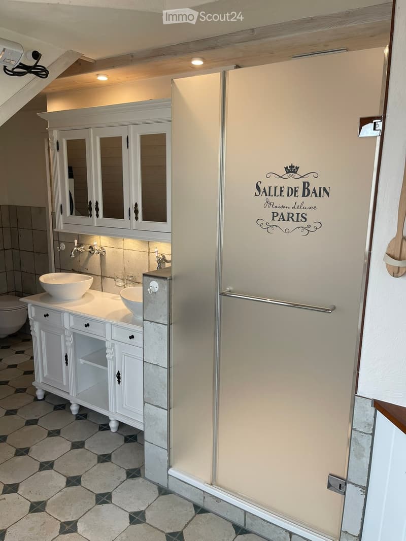 Elegant bathroom with white cabinetry, double sinks, mirrors, and a decorative sign reading "SALLE DE BAIN Maison deluxe PARIS".