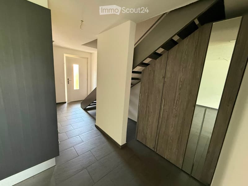 Modern hallway with wooden flooring, white walls, built-in storage cabinets, and a door leading to another room.