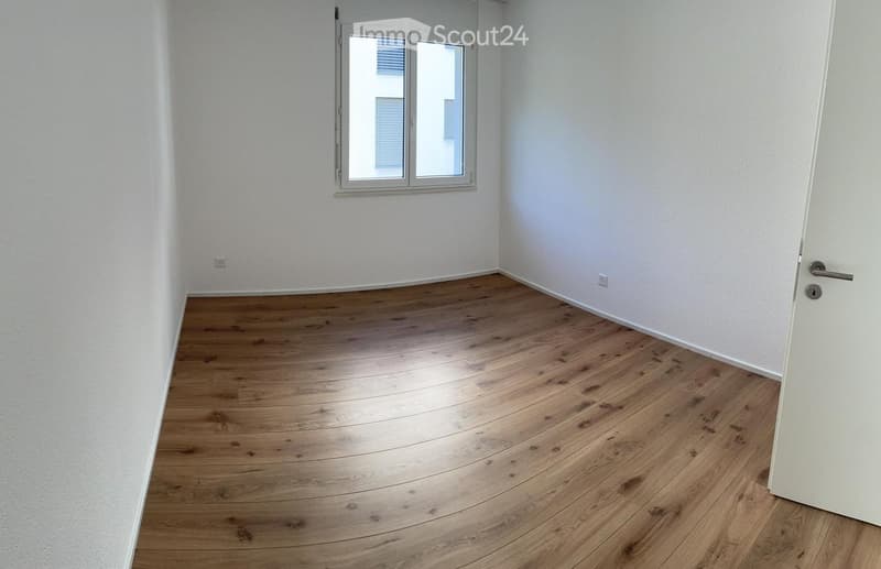 Empty room with light wooden flooring, white walls, and a window with blinds. No furniture or equipment is present.