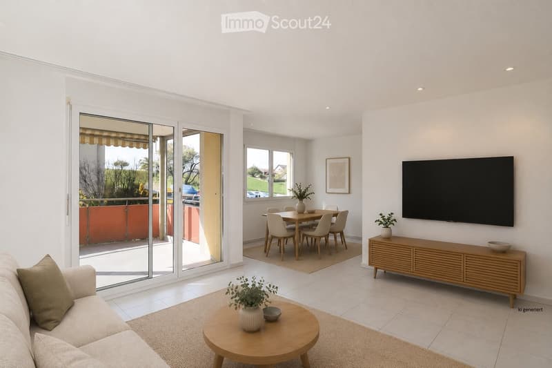 Bright living and dining area with white walls, tiled floor, large sliding glass doors leading to a balcony, sofa, coffee table, TV, dining table, and chairs.