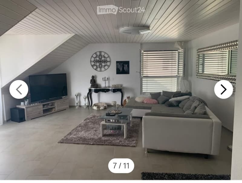 Modern living room with a grey sectional sofa, coffee table, TV stand, side table, and decorative items including a clock and mirror.
