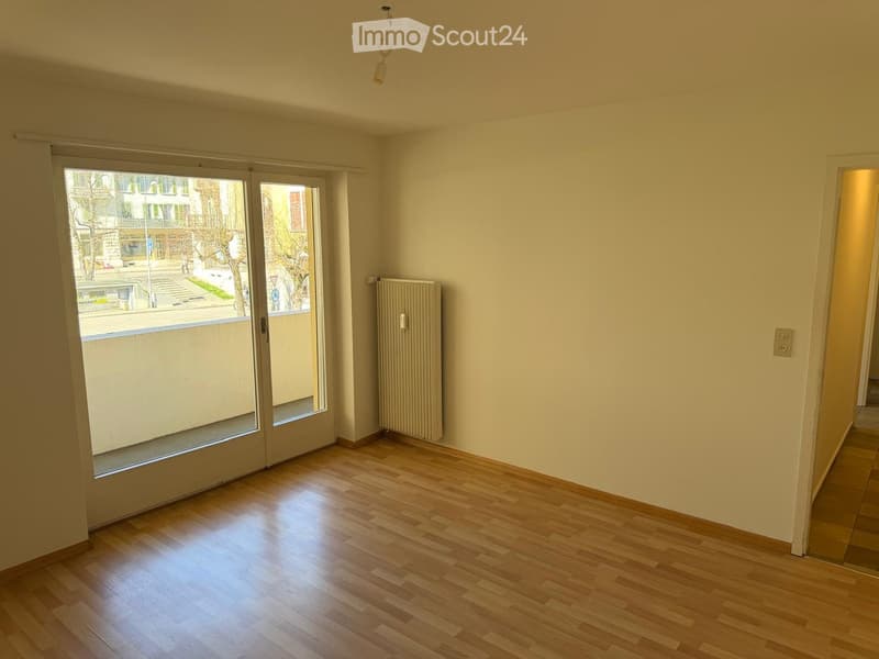 Empty room with wooden flooring, large sliding glass doors, radiator, and visible electrical outlets.