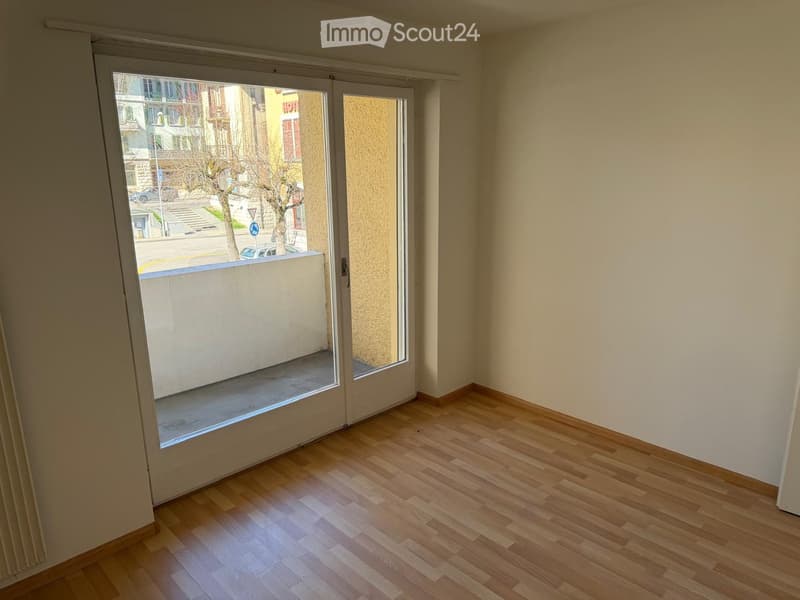 Empty room with wooden flooring and large sliding glass doors leading to a balcony area.