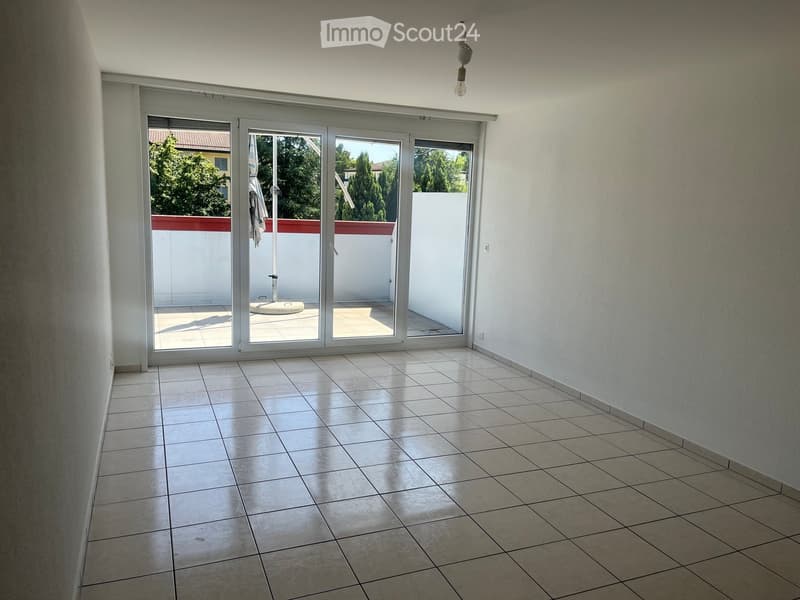 Empty room with tiled floor, white walls, and large sliding glass doors leading to a balcony.