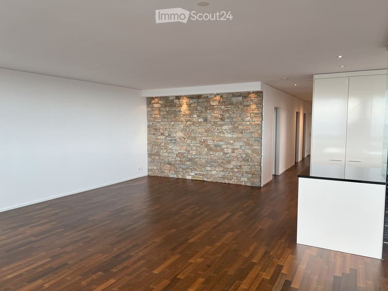 Empty room with wooden flooring, white walls, and a stone accent wall. No furniture or equipment present.